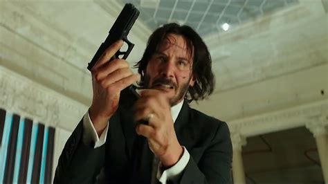 How does John Wick hold his gun?