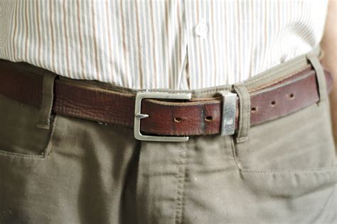 What is the proper way for a man to wear a belt?